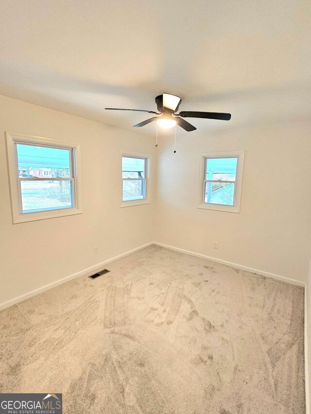 carpeted spare room with ceiling fan and plenty of natural light