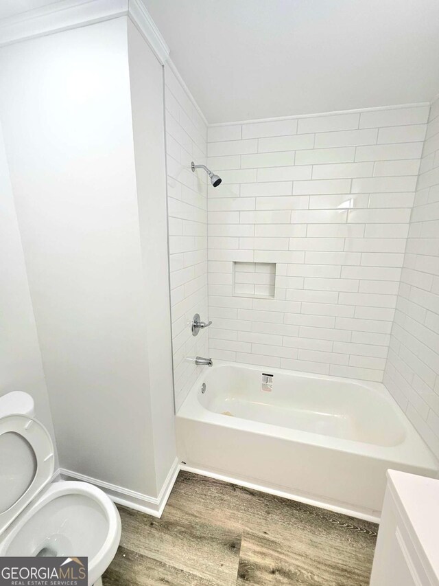 bathroom featuring hardwood / wood-style floors, tiled shower / bath combo, and toilet