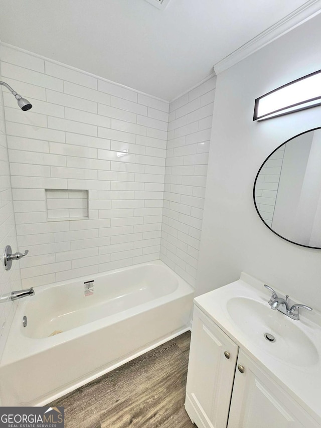 bathroom with vanity, hardwood / wood-style flooring, ornamental molding, and tiled shower / bath