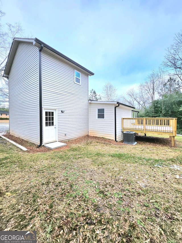 back of house featuring a lawn, a wooden deck, and central AC unit