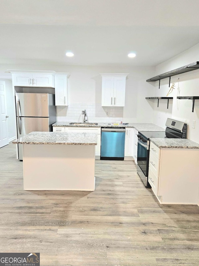 kitchen featuring backsplash, sink, light stone countertops, appliances with stainless steel finishes, and white cabinetry