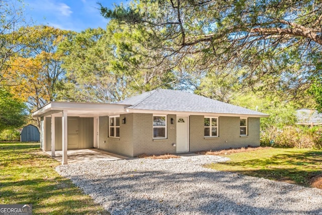 single story home featuring a front lawn, a storage unit, and a carport