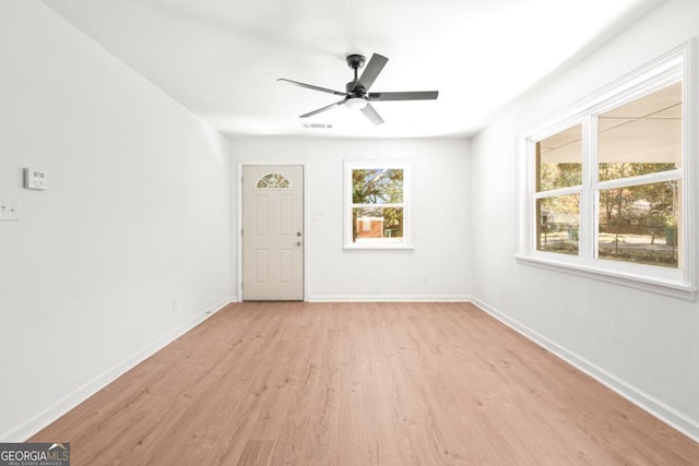 empty room with ceiling fan, plenty of natural light, and light hardwood / wood-style floors