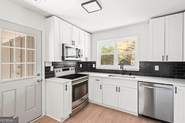 kitchen featuring appliances with stainless steel finishes, tasteful backsplash, white cabinetry, and sink