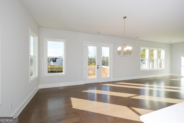 unfurnished room featuring dark hardwood / wood-style flooring, french doors, and an inviting chandelier