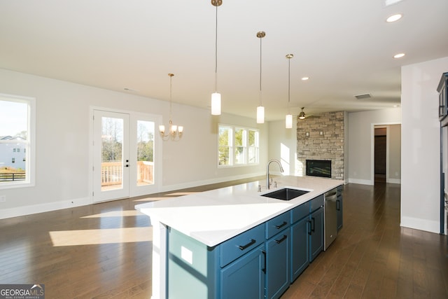 kitchen with dark hardwood / wood-style flooring, blue cabinets, sink, pendant lighting, and a center island with sink