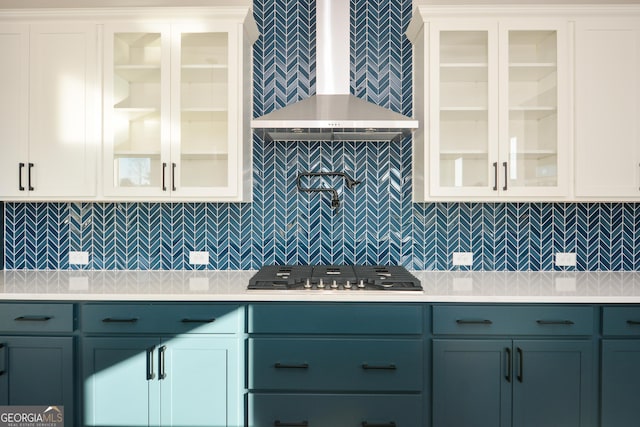 kitchen featuring decorative backsplash, white cabinetry, and wall chimney range hood