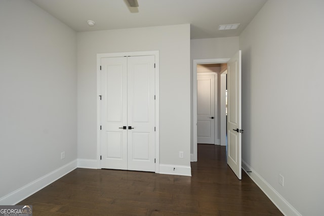 unfurnished bedroom featuring dark hardwood / wood-style flooring, a closet, and ceiling fan