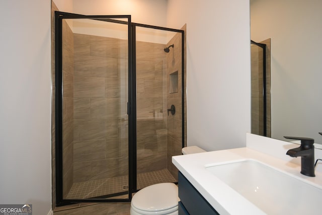 bathroom featuring vanity, toilet, and a shower with door