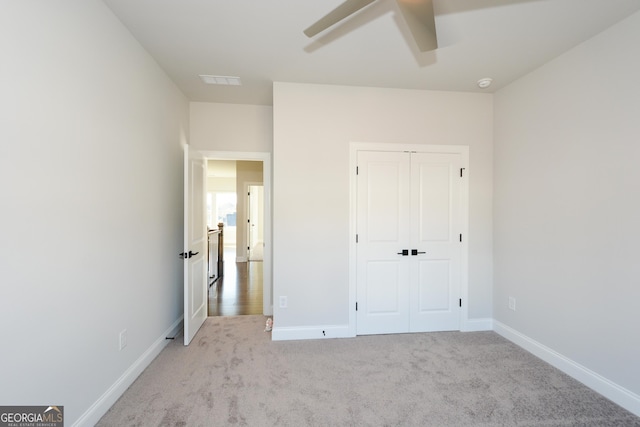 unfurnished bedroom featuring a closet, light colored carpet, and ceiling fan