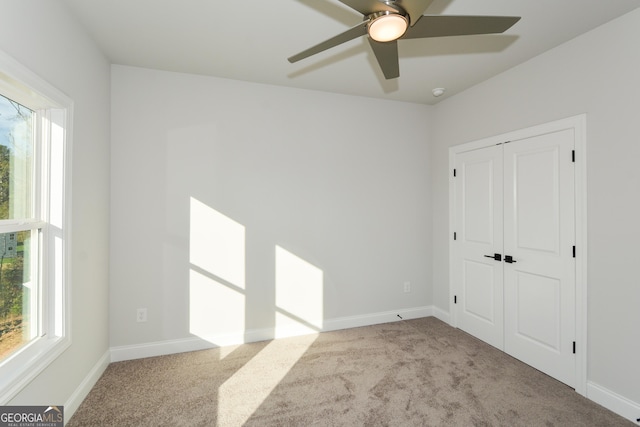 unfurnished bedroom featuring ceiling fan, light colored carpet, and a closet