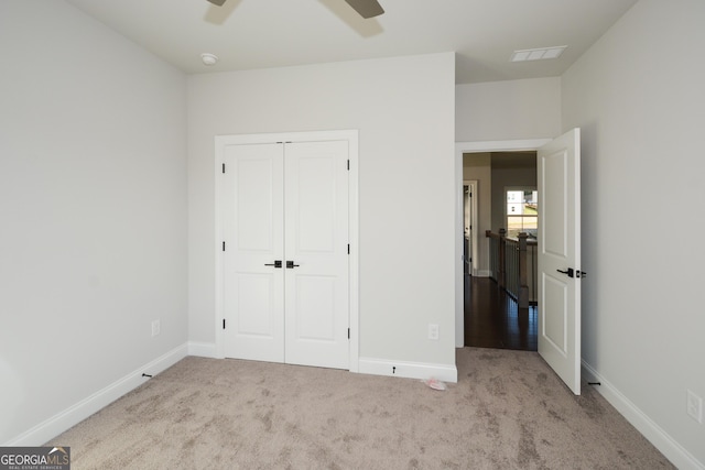 unfurnished bedroom with ceiling fan, a closet, and light colored carpet