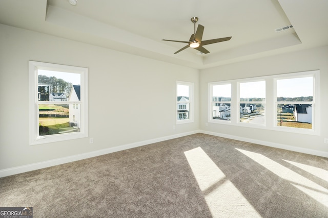 empty room featuring carpet flooring, ceiling fan, and a raised ceiling