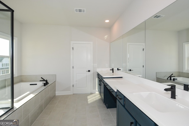 bathroom featuring tile patterned floors, vanity, and tiled tub