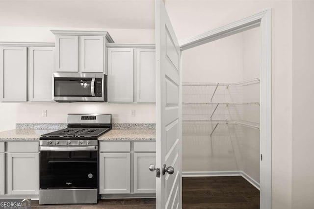 kitchen featuring white cabinets, dark hardwood / wood-style floors, light stone countertops, and appliances with stainless steel finishes