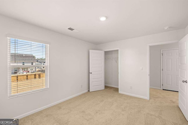 unfurnished bedroom with light carpet and a closet