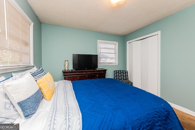 bedroom featuring hardwood / wood-style floors, a textured ceiling, and a closet