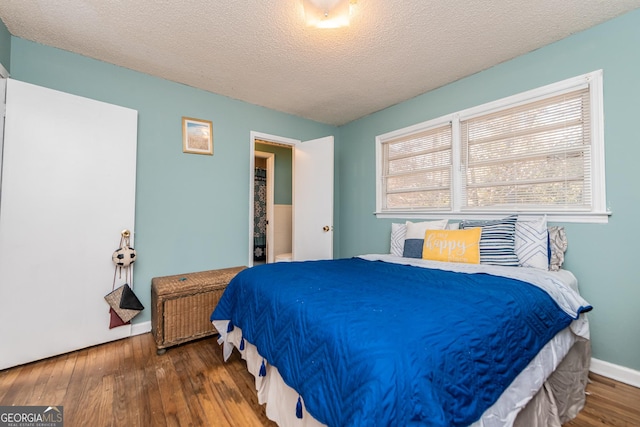 bedroom with a textured ceiling and dark hardwood / wood-style floors