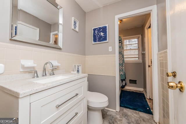 bathroom with vanity, toilet, and tile walls