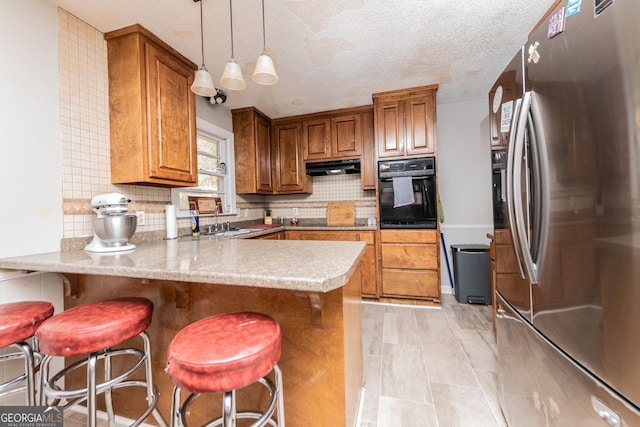 kitchen featuring black appliances, a kitchen bar, kitchen peninsula, and backsplash