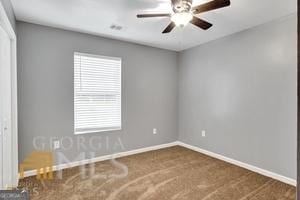 spare room with dark carpet and ceiling fan