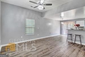 unfurnished living room featuring ceiling fan and dark wood-type flooring