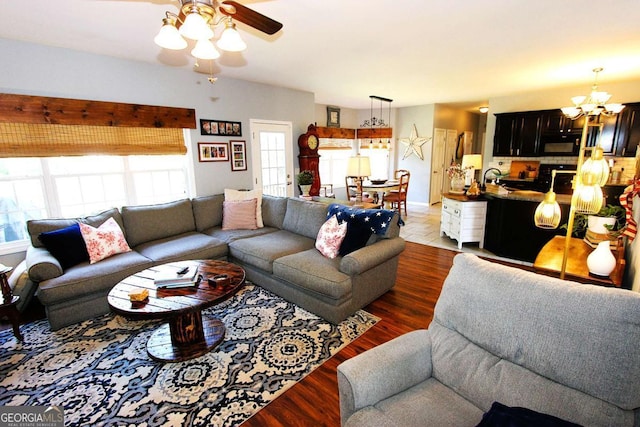 living room with ceiling fan with notable chandelier and dark hardwood / wood-style floors