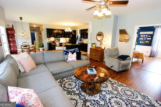 living room featuring ceiling fan with notable chandelier and dark wood-type flooring