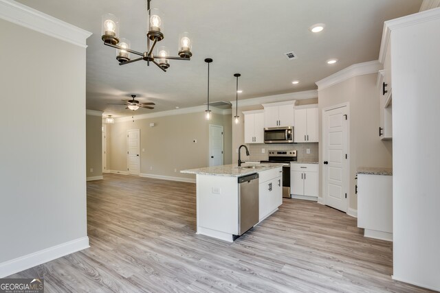 kitchen featuring ceiling fan with notable chandelier, hanging light fixtures, an island with sink, appliances with stainless steel finishes, and white cabinetry