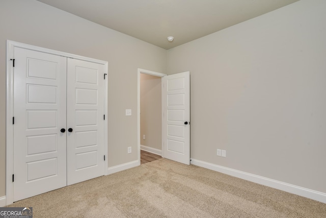 unfurnished bedroom featuring light carpet and a closet