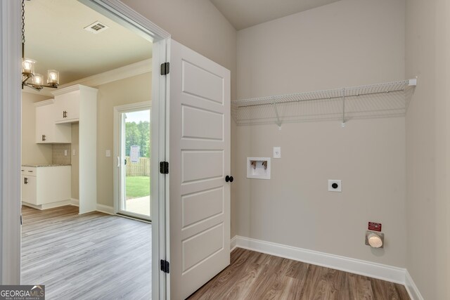 clothes washing area with washer hookup, hookup for an electric dryer, light hardwood / wood-style flooring, a notable chandelier, and crown molding