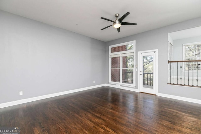 empty room with plenty of natural light, ceiling fan, and dark wood-type flooring