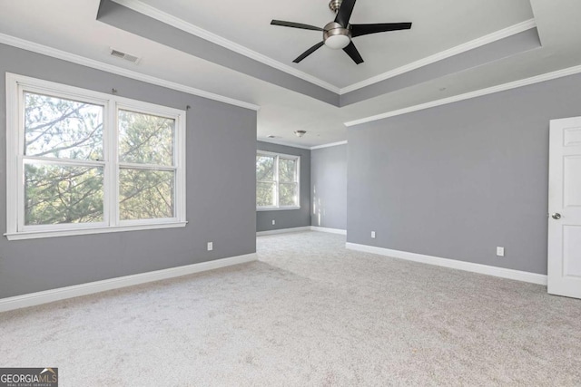 unfurnished room featuring a tray ceiling, ceiling fan, crown molding, and light colored carpet