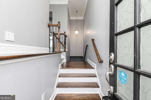 stairs featuring wood-type flooring and crown molding