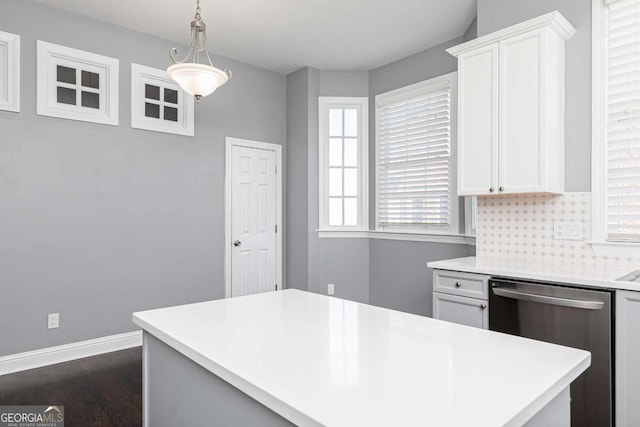 kitchen featuring backsplash, white cabinetry, stainless steel dishwasher, and hanging light fixtures