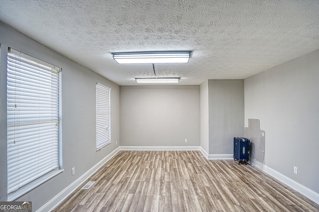 spare room featuring a textured ceiling and light hardwood / wood-style flooring