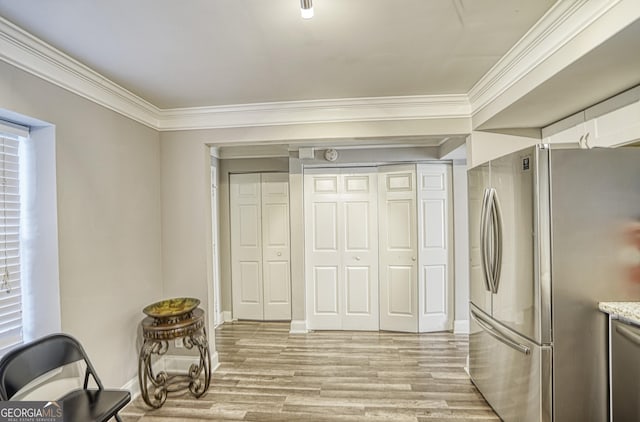 kitchen featuring appliances with stainless steel finishes, light hardwood / wood-style floors, white cabinetry, and crown molding