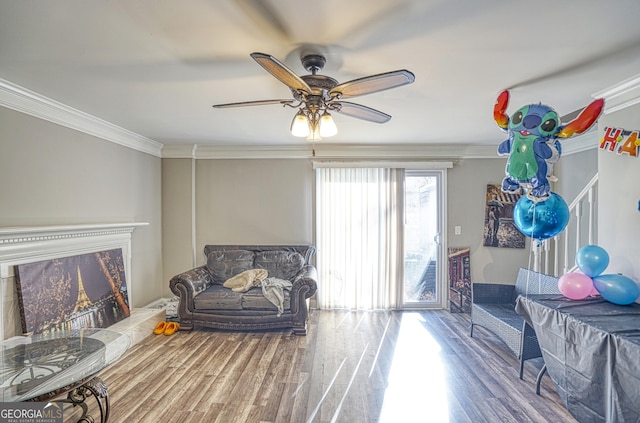 living room featuring crown molding, ceiling fan, and wood-type flooring