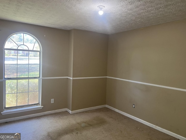 carpeted empty room featuring a textured ceiling