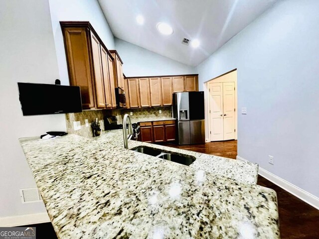 4140 Lanier Ridge Walk Unit 104, Cumming, GA 30041 - kitchen with appliances with stainless steel finishes, a peninsula, tasteful backsplash, light stone counters, and vaulted ceiling
