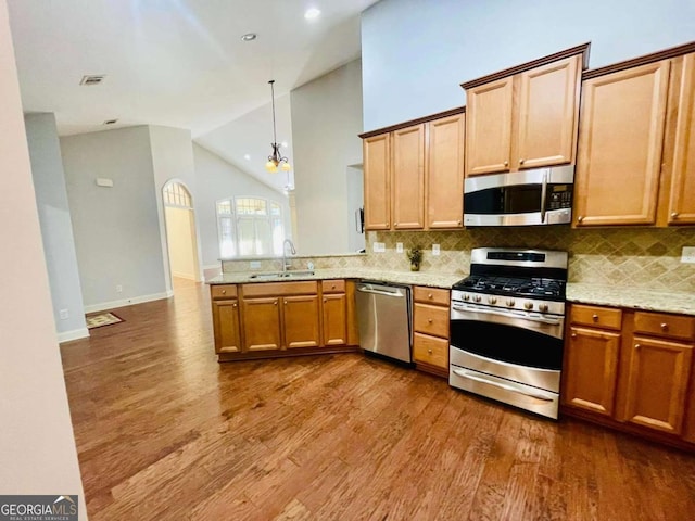 kitchen with sink, appliances with stainless steel finishes, light stone countertops, dark hardwood / wood-style flooring, and decorative light fixtures