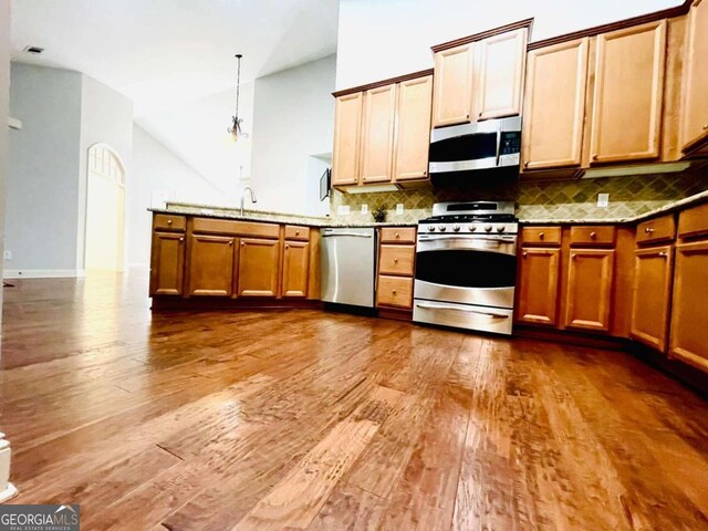 4140 Lanier Ridge Walk Unit 104, Cumming, GA 30041 - kitchen featuring appliances with stainless steel finishes, wood finished floors, tasteful backsplash, a peninsula, and lofted ceiling