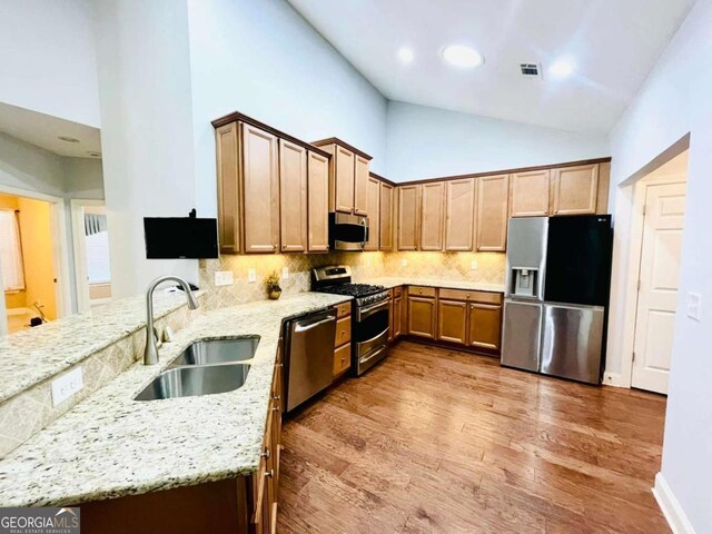 4140 Lanier Ridge Walk Unit 104, Cumming, GA 30041 - kitchen featuring appliances with stainless steel finishes, a peninsula, light stone counters, light wood finished floors, and high vaulted ceiling