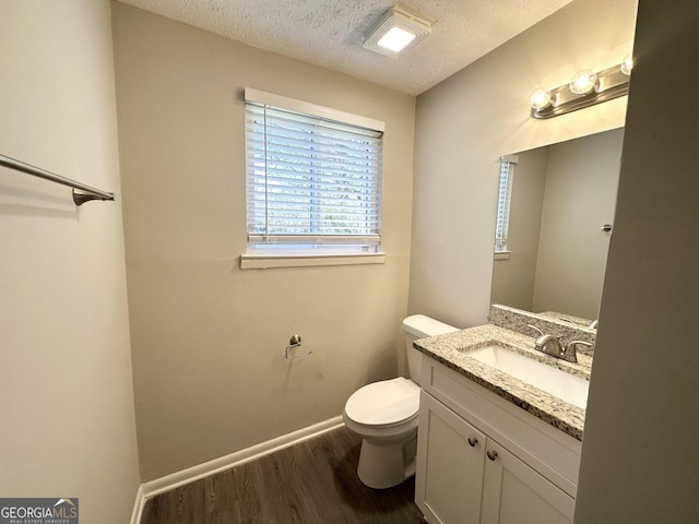 bathroom with hardwood / wood-style floors, vanity, a textured ceiling, and toilet