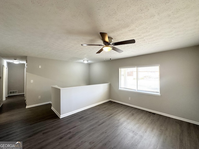 unfurnished room featuring ceiling fan, dark wood-type flooring, and a textured ceiling