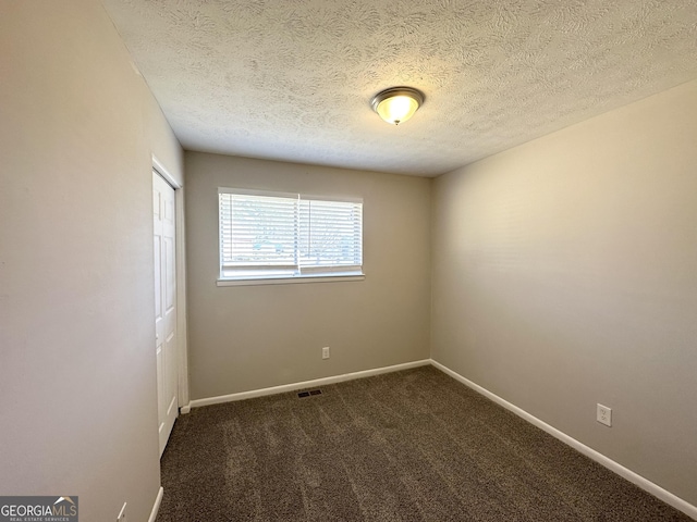 carpeted empty room with a textured ceiling