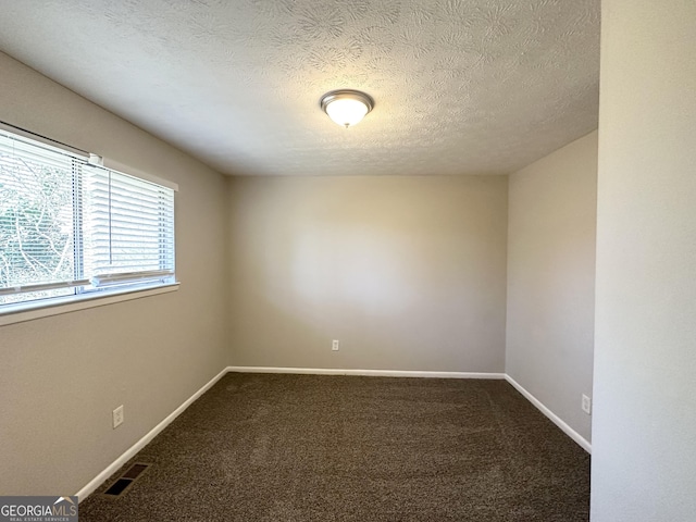 carpeted empty room featuring a textured ceiling