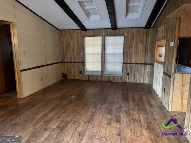 spare room featuring hardwood / wood-style floors, beam ceiling, and wood walls