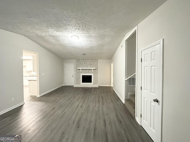 unfurnished living room with a textured ceiling, dark hardwood / wood-style flooring, a fireplace, and vaulted ceiling