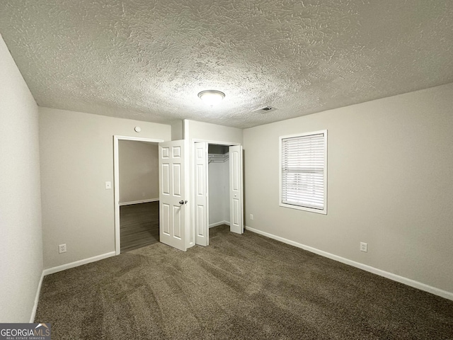 unfurnished bedroom featuring dark colored carpet, a textured ceiling, and a closet